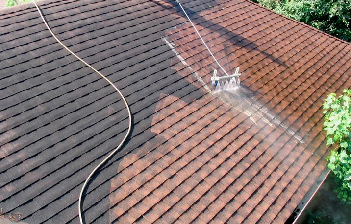 A shingle roof half washed: dark and stained on the left, clean and warm on the right